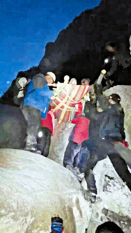 救援隊(duì)員用自制的簡(jiǎn)易擔(dān)架抬傷者。